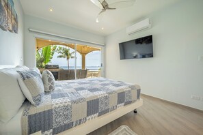 A bedroom with a bed, a TV, and a view of the outdoors. - Oceanfront 3BR Condo in Playa Potrero (Playa Potrero)