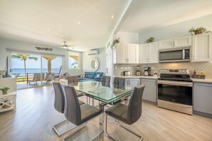A modern kitchen with a glass dining table, stainless steel appliances, and a view of the ocean. - Oceanfront 3BR Condo in Playa Potrero (Playa Potrero)