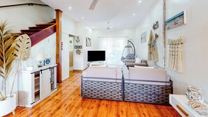 Ampla sala de estar com escada de madeira, TV de tela plana e decoração náutica.