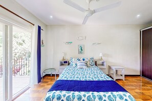 A bedroom with a bed, a ceiling fan, a nightstand, a lamp, and a view of the outdoors. - Walk to Tamarindo Beach! Condo w/ 2 Balconies (Tamarindo)