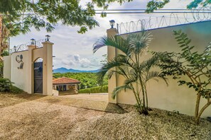 A gated entrance with a mountain view, a covered patio, and a palm tree. - Walk to Ocean! Flamingo Beach Condo w/ Pool Access (Flamingo Beach)