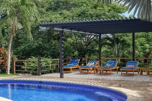 A pool area with lounge chairs and a pergola. - Walk to Ocean! Flamingo Beach Condo w/ Pool Access (Flamingo Beach)