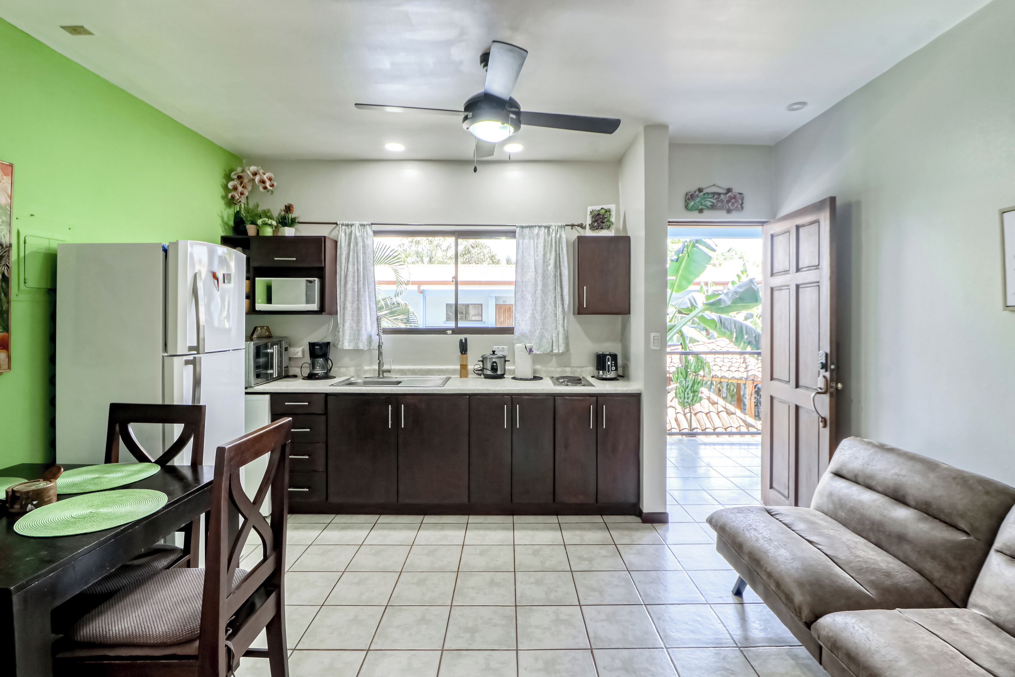 A compact kitchen with a dining area, a ceiling fan, and a view to the outside.