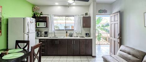 A compact kitchen with a dining area, a ceiling fan, and a view to the outside.