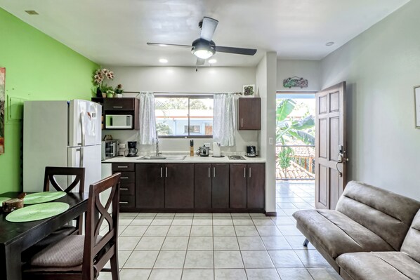 A compact kitchen with a dining area, a ceiling fan, and a view to the outside. - Pool, Walk to Beach: Playas del Coco Studio (Playas del Coco)