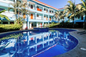 Un hôtel doté d’une piscine, de nombreux balcons et de palmiers.