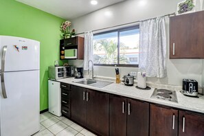 A kitchen with a refrigerator, microwave, sink, and various appliances. - Pool, Walk to Beach: Playas del Coco Studio (Playas del Coco)