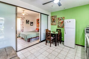 A room with a bed, a dining table with chairs, a refrigerator, and a ceiling fan. - Pool, Walk to Beach: Playas del Coco Studio (Playas del Coco)