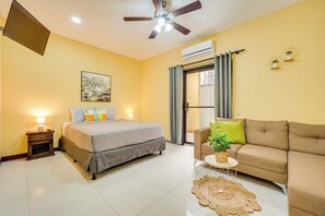 A hotel room with a bed, a sofa, a small table with a plant, a ceiling fan, and an air conditioning unit. - Family Retreat w/ Pool Access: Walk to Beach! (Playas del Coco)