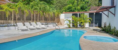 A swimming pool with lounge chairs and a small building with a red roof.