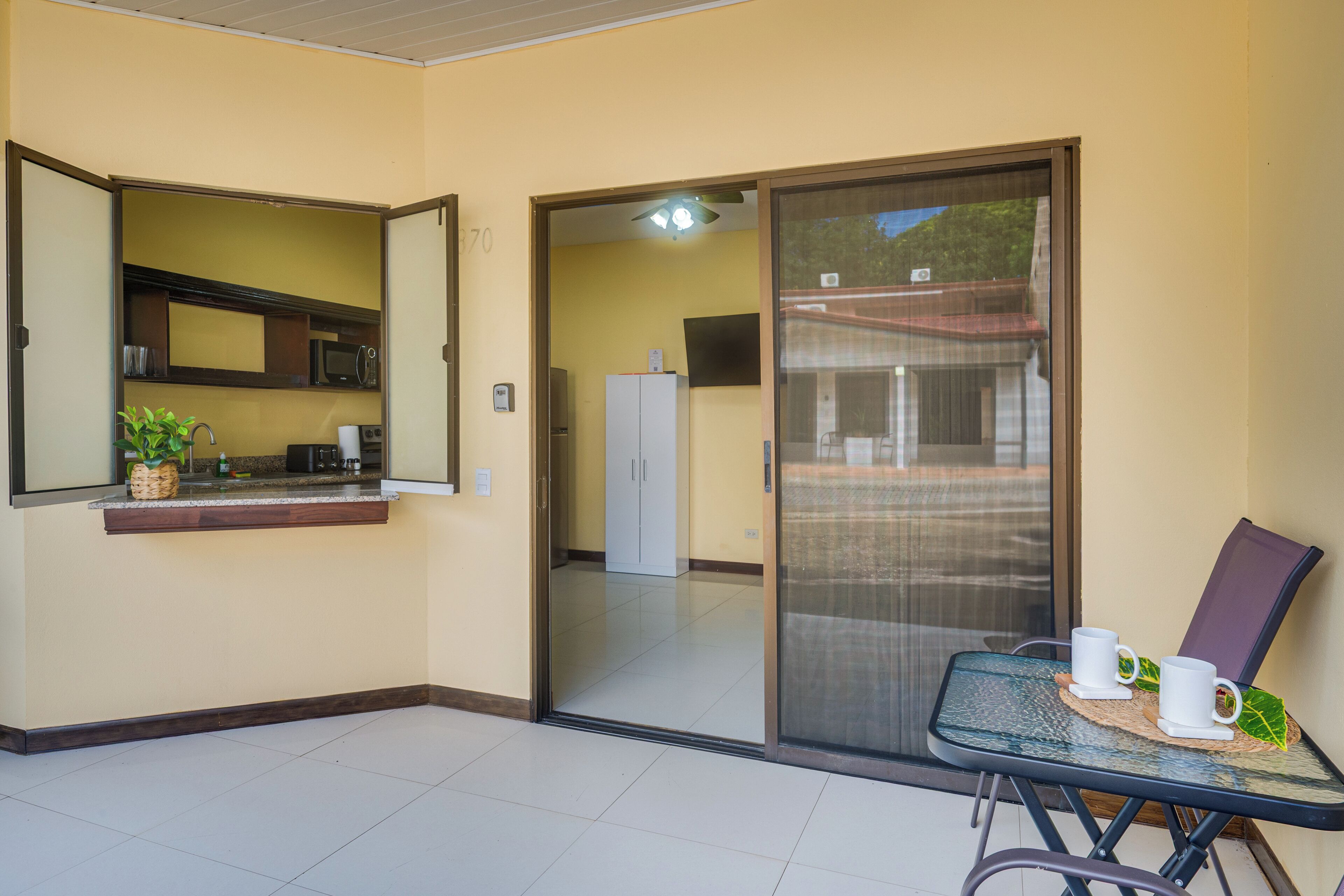 Een kamer met een kitchenette, een schuifdeur naar een buitenruimte en een tafel met stoelen.