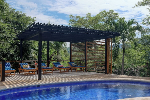 Ein Poolbereich mit Liegestühlen und einer Pergola.