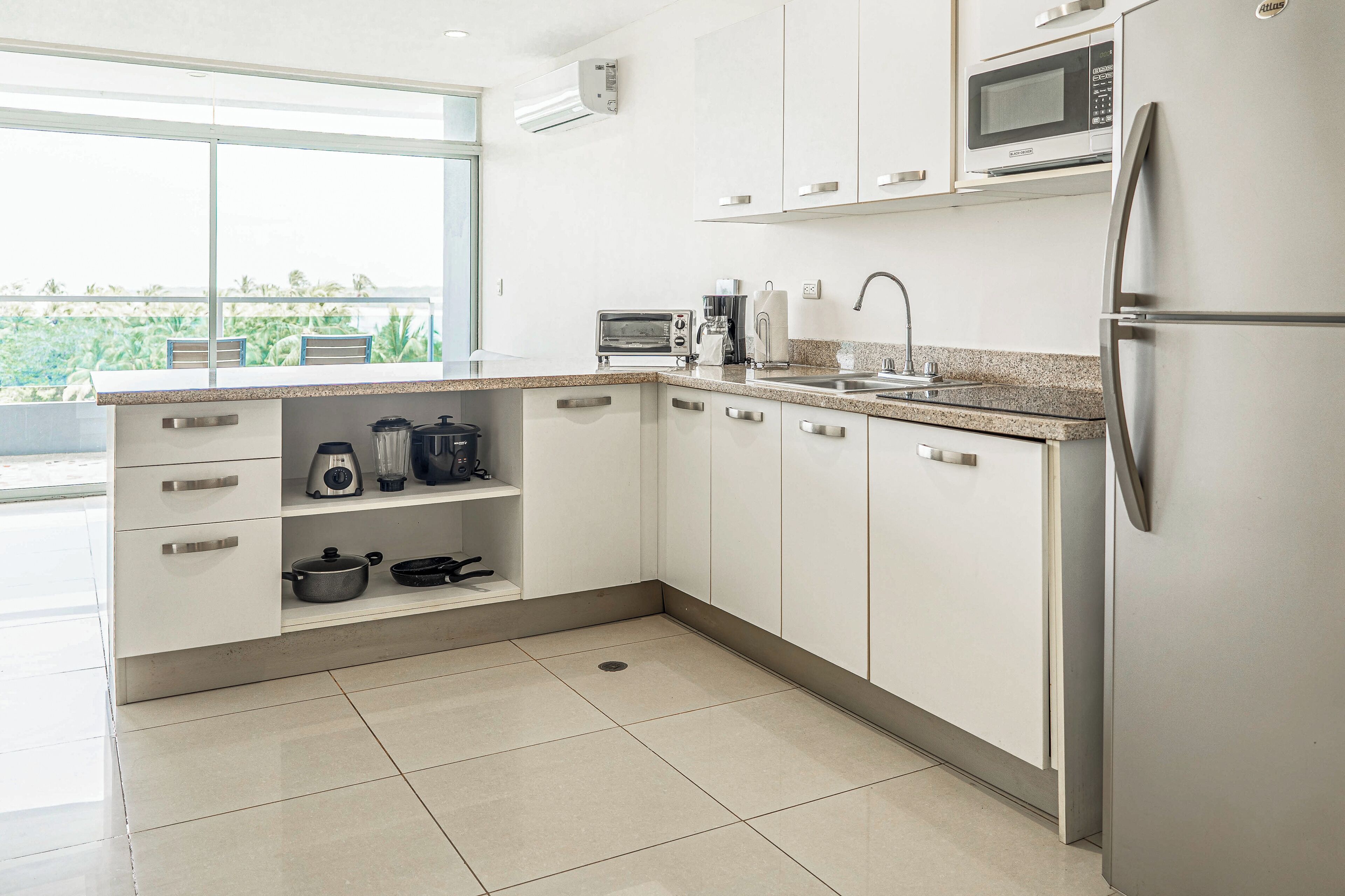 A modern kitchen with white cabinets, a stainless steel refrigerator, a microwave, and a coffee maker.
