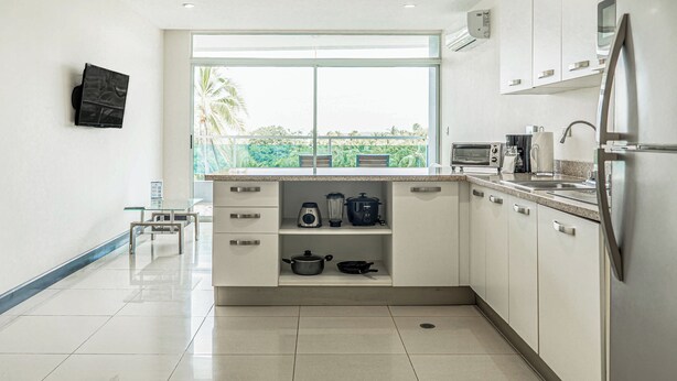 A modern kitchen with a large window, stainless steel appliances, and a tiled floor.