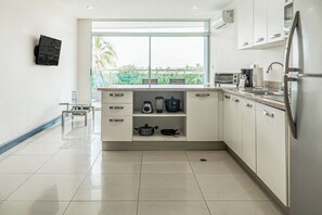 Een moderne keuken met een groot raam, roestvrijstalen apparatuur en een betegelde vloer.
