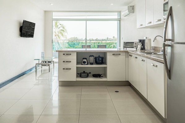 A modern kitchen with a large window, stainless steel appliances, and a tiled floor.