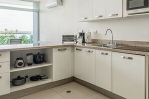 A kitchen with white cabinets, a granite countertop, a toaster, a coffee maker, and a sink.
