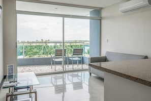 A modern living room with a glass door leading to a balcony, a sofa, a coffee table, and two chairs.