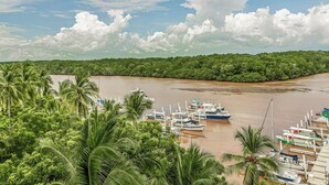 A riverfront with boats docked, surrounded by dense green foliage.