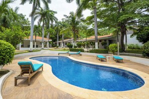 Un complexe hôtelier doté d’une piscine, de chaises longues et de palmiers.