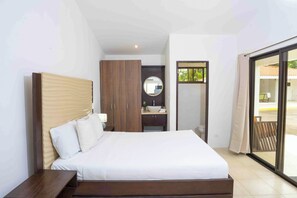 A bedroom with a bed, a wooden wardrobe, a bathroom with a sink, and a sliding glass door leading to an outdoor area. - Ground-Floor Studio w/ Pool Access, Walk to Beach! (Playas del Coco)