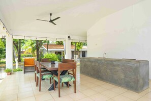 Un espace extérieur abrité, aménagé pour les repas, avec une table, des chaises et un bar intégré.