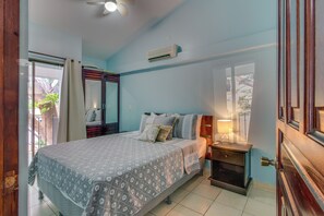A bedroom with a bed, bedside table, and a window. - Playas del Coco Condo: Walk to Beach & Restaurants (Playas del Coco)