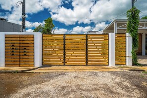 A gated entrance with a wooden fence and a white wall. - < 1 Mi to Playas del Coco: Studio w/ Pool Access! (Playas del Coco)