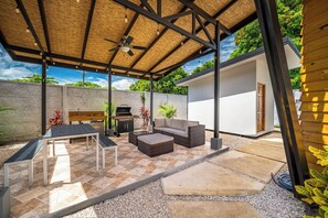 Une terrasse extérieure dotée d’un toit de chaume, de murs en pierre et d’un espace salon avec un canapé et une table.