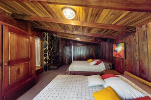Une pièce en bois avec deux lits, un mur en pierre et un tableau accroché au mur.