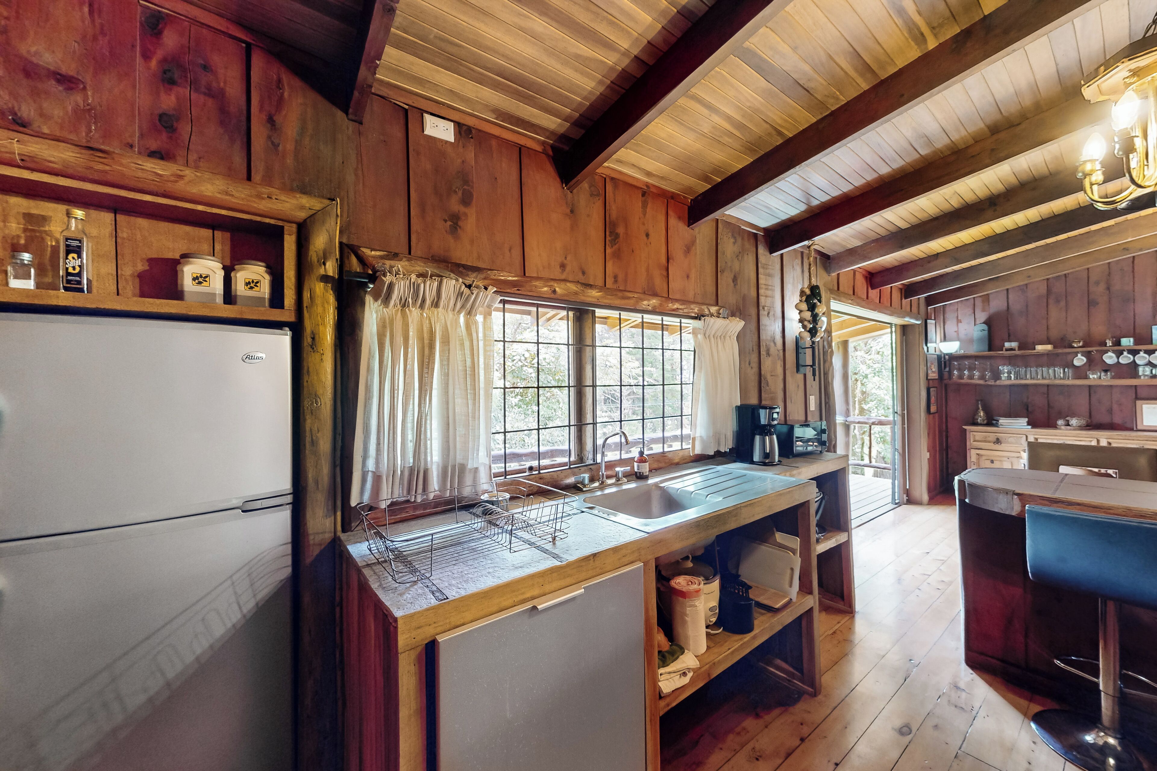 Una cucina rustica con pareti in legno, un frigorifero bianco, un lavello con scolapiatti e una macchina da caffè.