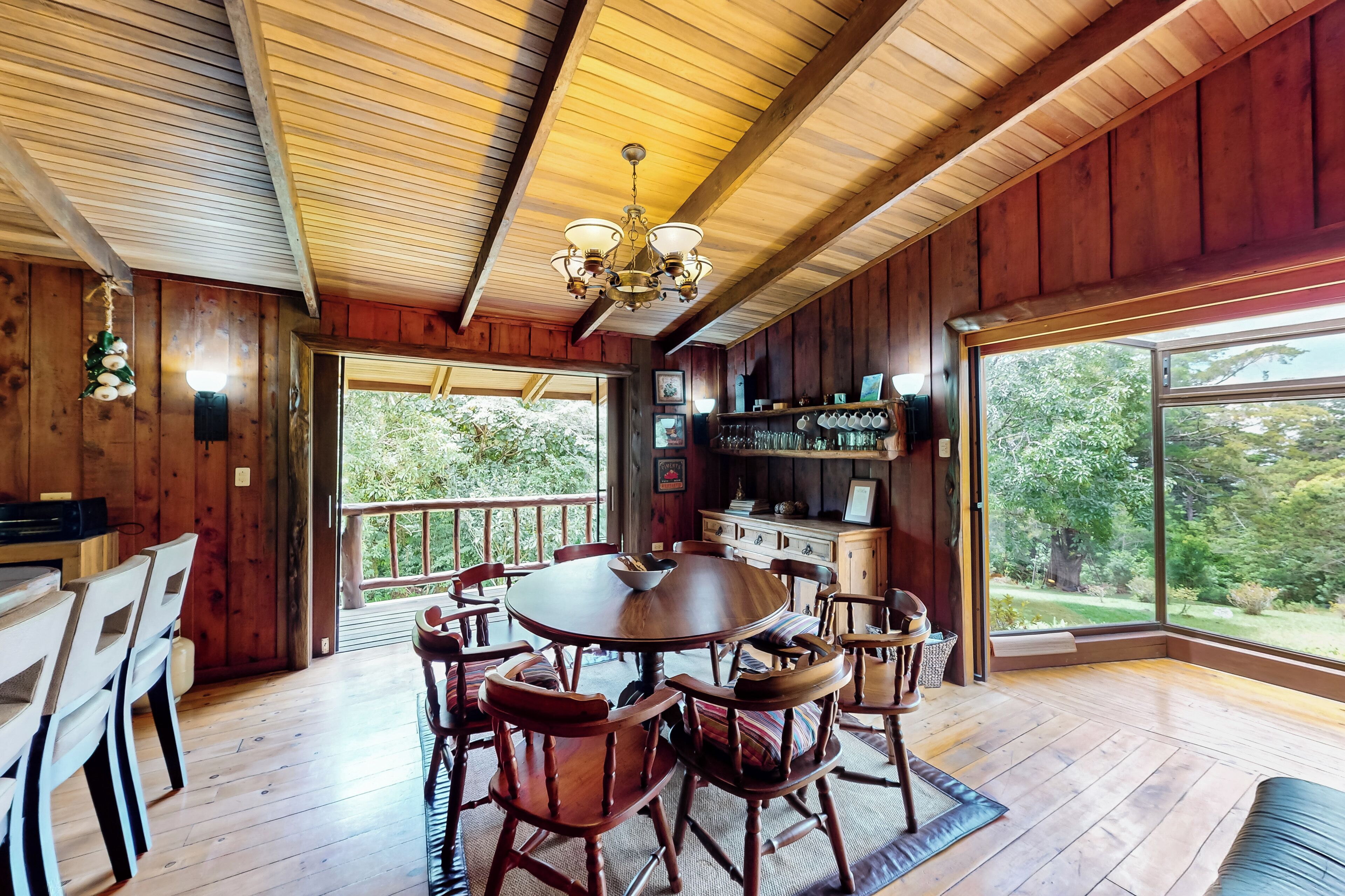 A wooden interior with a dining area, a bar, and large windows offering a view of the outdoors.