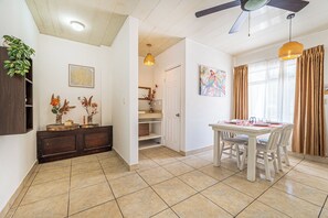 A dining area with a table and chairs, a ceiling fan, and a window with curtains. - Playas del Coco Condo w/ Pool: Walk to Beach! (Playas del Coco)