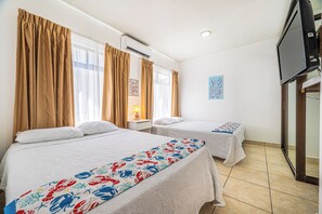 A hotel room with two beds, a television, and a window with curtains. - Playas del Coco Condo w/ Pool: Walk to Beach! (Playas del Coco)