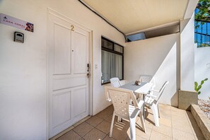 Eine weiße Tür mit einer Nummer, ein Fenster mit Vorhängen, ein Tisch mit Stühlen und ein Schild über der Tür.