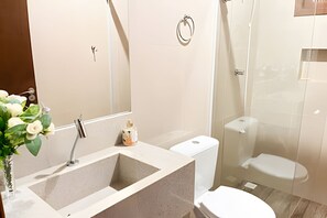 Un baño con lavamanos, espejo, inodoro y ducha.