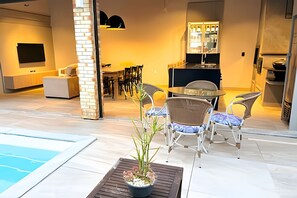 Una cocina moderna con comedor, piscina y una planta en maceta.
