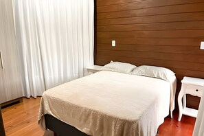 Un dormitorio con cama, mesita de noche y cabecera de madera.