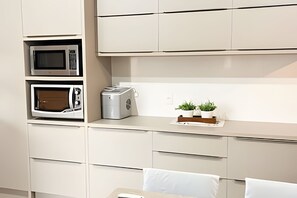 A kitchenette with a microwave, toaster, and a small plant on the countertop.