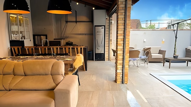 Ein modernes Interieur mit einer Couch, einem Esstisch, Stühlen und einem Poolbereich.