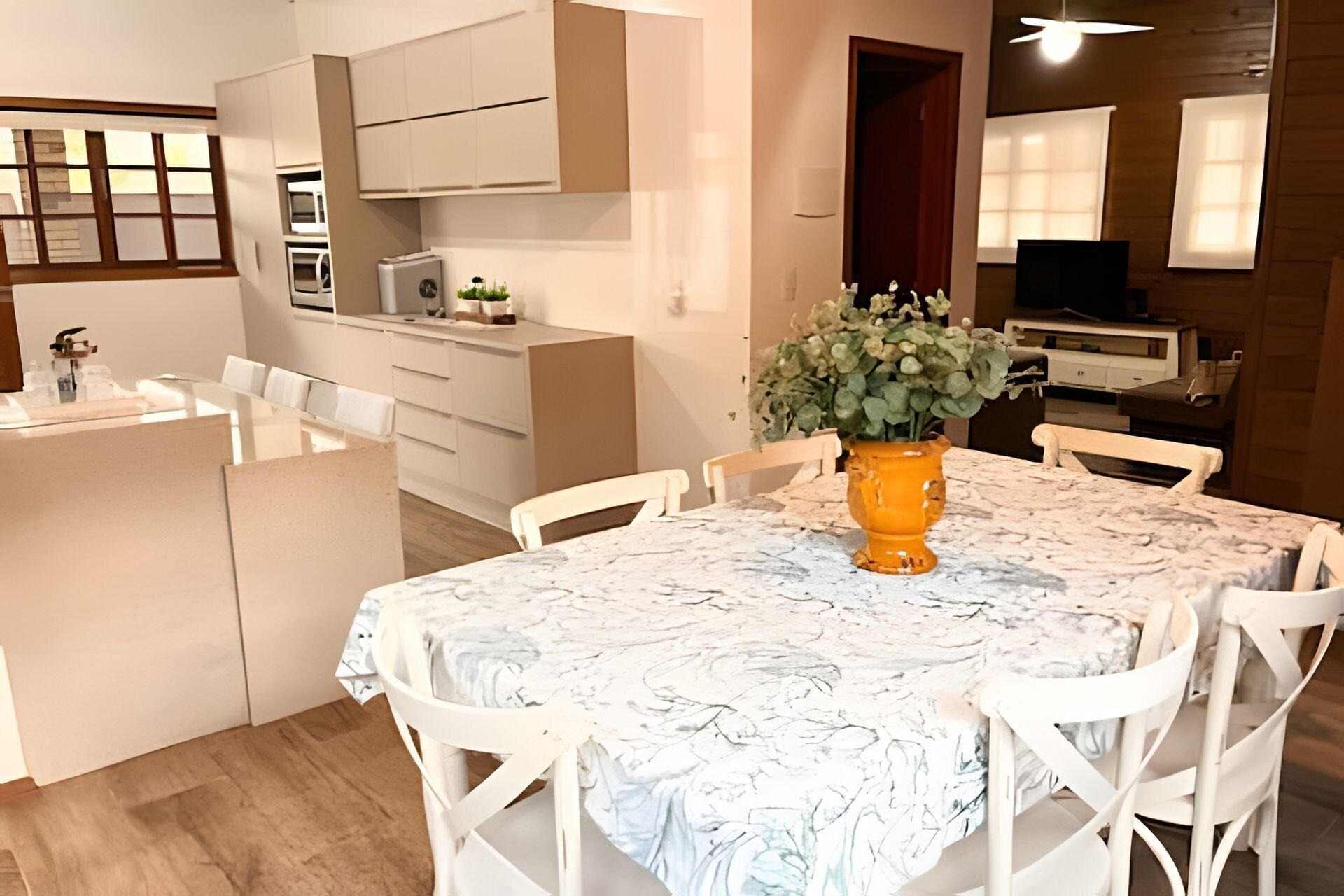 A modern kitchen with white cabinetry, a dining area with a marble table, and a small island with a sink.