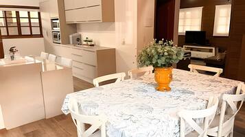 A modern kitchen with white cabinetry, a dining area with a marble table, and a small island with a sink.