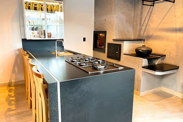 A modern kitchen with a central island, bar stools, a gas stove, and a built-in oven.