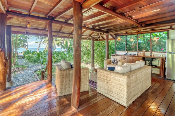 Un espace extérieur aménagé avec des meubles en osier, un plancher en bois et une vue sur l’océan.