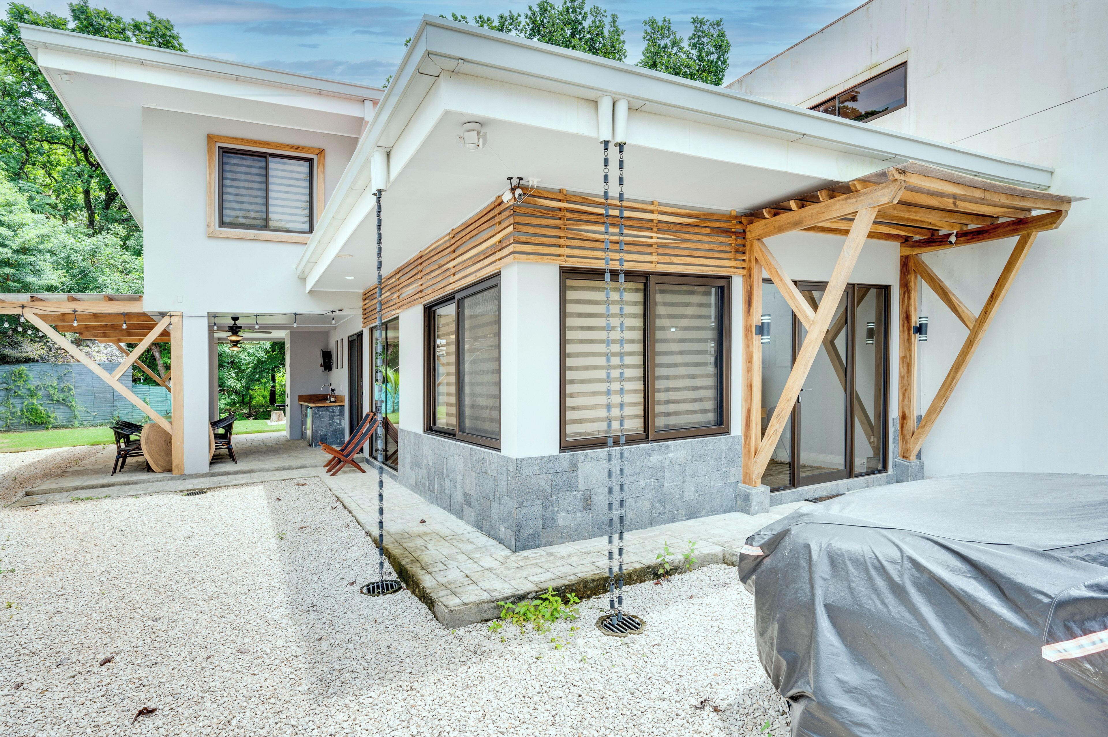 A modern two-story house with a covered patio, a swing, and a covered outdoor seating area.