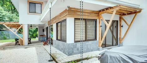 A modern two-story house with a covered patio, a swing, and a covered outdoor seating area.