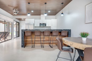 A modern kitchen with white cabinets, a central island with bar stools, and a dining table with chairs. - 3 Mi to Playa Avellana! Modern Home w/ Pool Access (Playa Avellanas)