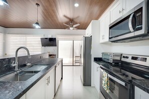 Een moderne keuken met een granieten aanrechtblad, roestvrijstalen apparatuur en een plafondventilator.