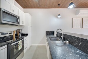 A modern kitchen with white cabinets, a black countertop, stainless steel appliances, and a marble backsplash. - 3 Mi to Playa Avellana! Modern Home w/ Pool Access (Playa Avellanas)