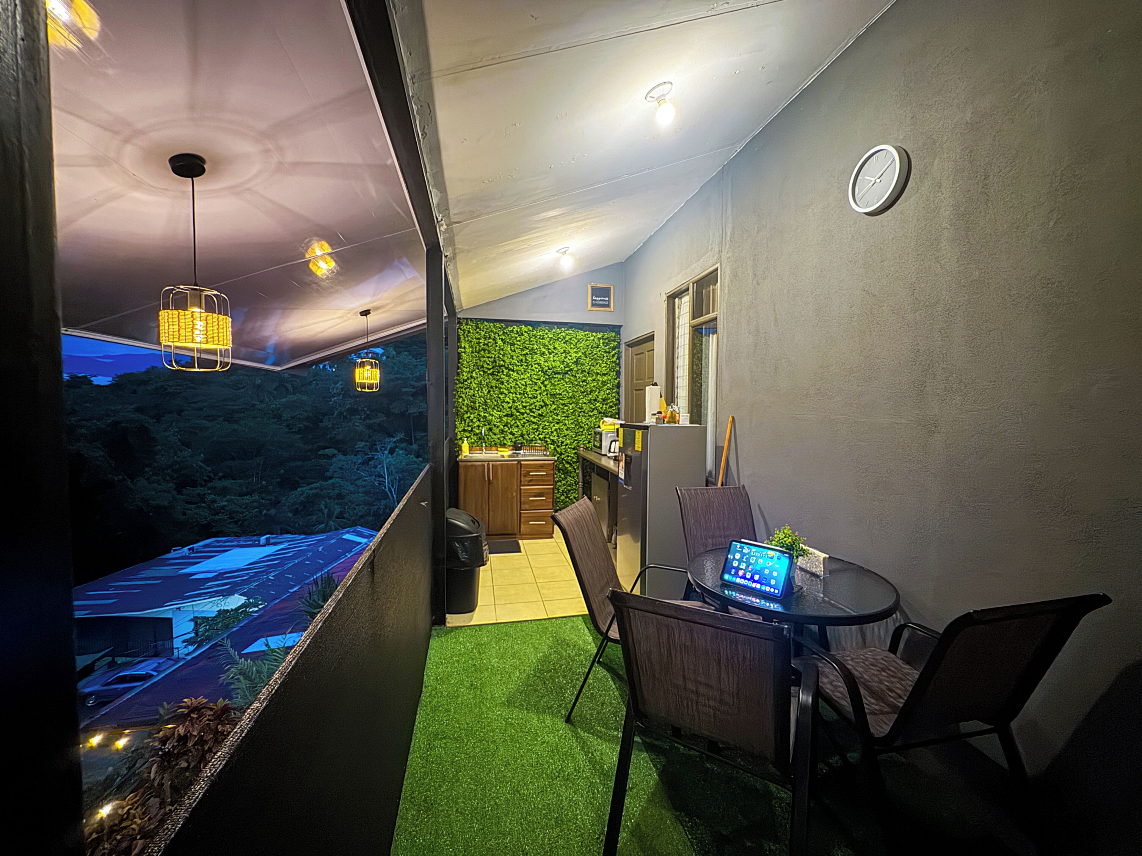 A narrow hallway with a green wall, a small seating area with a laptop, and a view of a parking lot outside.